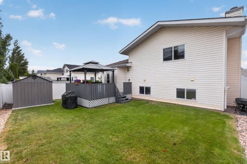 Expansive backyard featuring a manicured lawn, a grey storage shed, and a raised deck with a black gazebo - 365 Hollick-Kenyon Road Nw, Edmonton, AB 