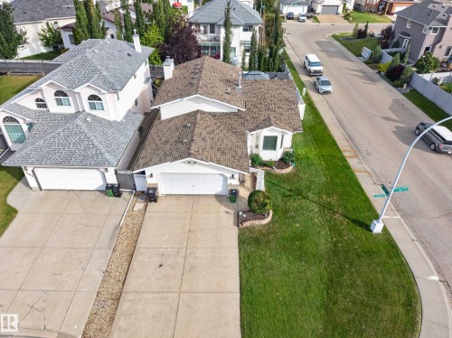 Exterior featuring a shingle roof, attached garage, concrete driveway, and a front lawn with established landscaping - 365 Hollick-Kenyon Road Nw, Edmonton, AB 