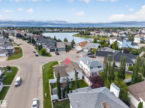 Aerial perspective of a residential neighborhood featuring a large body of water, multiple homes with varied architectural styles, and established landscaping - 365 Hollick-Kenyon Road Nw, Edmonton, AB 