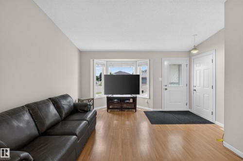 Wood-finish flooring, bay window, light neutral wall tones, white trim, and a paneled entry door - 365 Hollick-Kenyon Road Nw, Edmonton, AB 