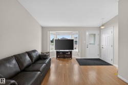 Wood-finish flooring, bay window, light neutral wall tones, white trim, and a paneled entry door - 