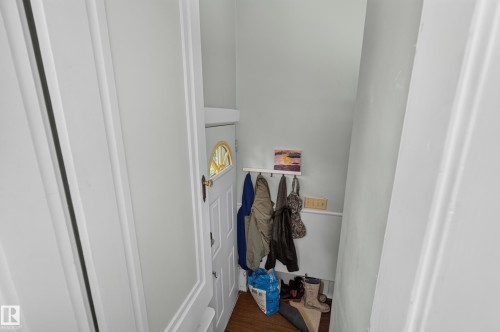 White paneled door with a semi-circular decorative window, light-colored walls, and wood-finish flooring - 11308 123 Street Nw, Edmonton, AB 