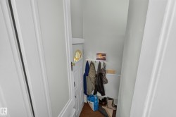 White paneled door with a semi-circular decorative window, light-colored walls, and wood-finish flooring - 