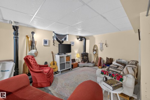 Recessed wood-burning stove with a stone hearth, drop ceiling, and light-toned wall finishes - 11308 123 Street Nw, Edmonton, AB 