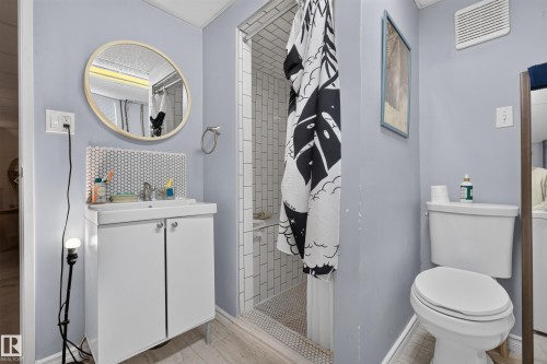 White vanity with an integrated sink, round mirror, and hexagonal tile backsplash - 11308 123 Street Nw, Edmonton, AB 