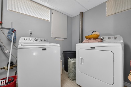 Laundry area featuring a top-load washing machine, front-load dryer, and light-toned flooring - 11308 123 Street Nw, Edmonton, AB 