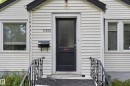 White horizontal siding exterior with a black entry door featuring a frosted glass panel - 11308 123 Street Nw, Edmonton, AB 