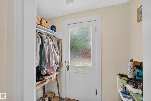 Entryway featuring a white door with privacy glass, built-in open closet with shelving, and overhead flush-mount lighting - 11308 123 Street Nw, Edmonton, AB 