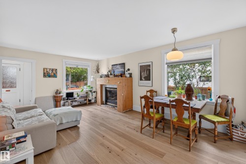 Wood-finish flooring throughout, a built-in fireplace with a wood surround, and multiple windows providing natural illumination - 11308 123 Street Nw, Edmonton, AB 