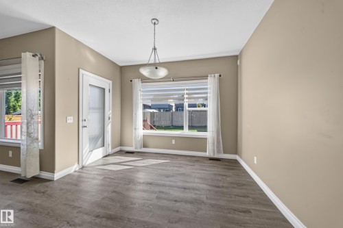 Wood-finish flooring, white baseboards, and a glass-paneled door - 121 64 Street Sw, Edmonton, AB 