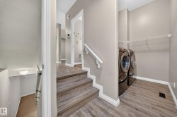 Wood-finish flooring throughout, featuring a built-in laundry area with shelving - 