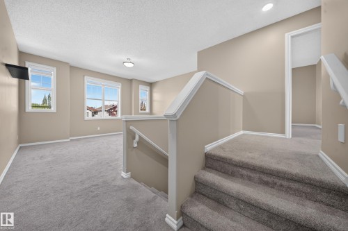Carpeted stairs leading to a carpeted upper level, featuring multiple windows, recessed lighting, and a flush mount ceiling fixture - 121 64 Street Sw, Edmonton, AB 