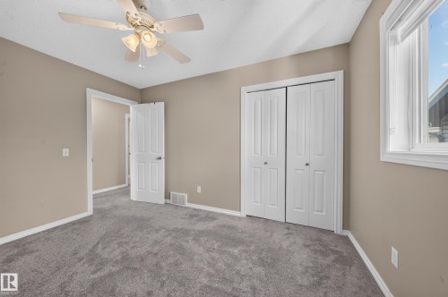 Neutral wall paint, gray carpeting, bi-fold closet doors, white trim, and a ceiling fan with integrated lighting - 121 64 Street Sw, Edmonton, AB 