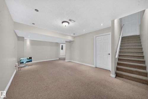 Carpeted flooring, recessed lighting, white trim, paneled interior door, and a staircase with a handrail - 121 64 Street Sw, Edmonton, AB 