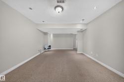 Spacious room featuring neutral carpeting, light gray wall paint, recessed lighting, and a drop ceiling with a central flush mount light fixture - 