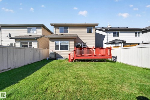 Expansive fenced backyard with a red-stained wood deck and a well-maintained lawn - 121 64 Street Sw, Edmonton, AB 