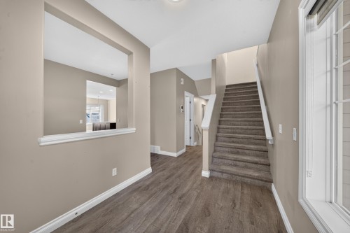 Wood-finish flooring, neutral wall tones, carpeted staircase, open pass-through, and white trim throughout - 121 64 Street Sw, Edmonton, AB 