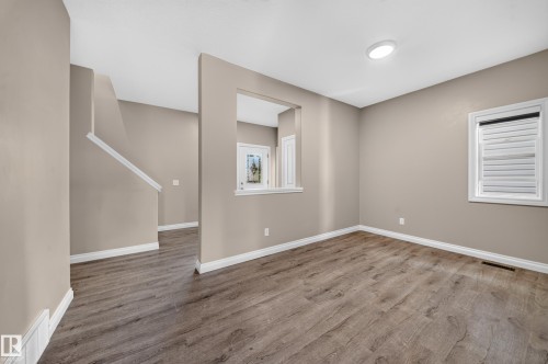 Wood-finish flooring, neutral wall paint, white trim, recessed ceiling lighting, and a white framed window - 121 64 Street Sw, Edmonton, AB 