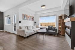 Spacious living area featuring wood-finish flooring, a tray ceiling, and an expansive window - 