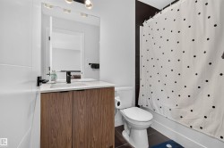 Bathroom featuring a wood-finish vanity with a white countertop, undermount sink, and matte black faucet - 