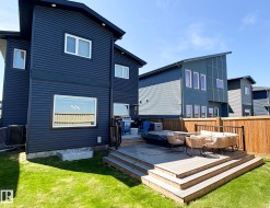 Expansive backyard featuring a multi-level composite deck, mature wooden fencing, and a manicured lawn - 