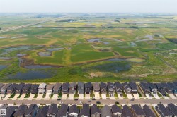 Aerial perspective showcasing a structured residential area bordering expansive green fields - 