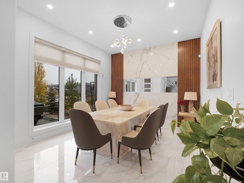 Large windows, recessed lighting, polished white tile flooring, decorative wood paneling, and a contemporary chandelier - 4809 Woolsey Lane Nw, Edmonton, AB 