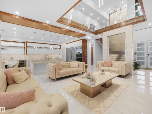 Open-concept living area featuring a large kitchen island, integrated appliances, recessed lighting, and a prominent interior water feature - 4809 Woolsey Lane Nw, Edmonton, AB 