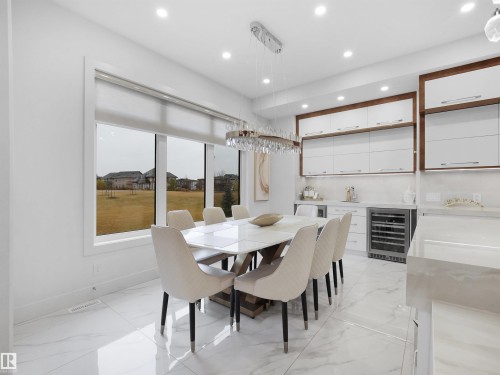 Marble-look tile flooring, built-in cabinetry with wood-finish framing, large window with roller shade, recessed lighting, and a crystal chandelier - 4809 Woolsey Lane Nw, Edmonton, AB 