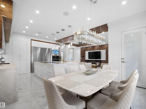 Expansive kitchen island with integrated cooktop, dual wall ovens, and stainless steel French door refrigerator - 4809 Woolsey Lane Nw, Edmonton, AB 