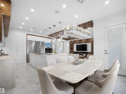 Expansive kitchen island with integrated cooktop, dual wall ovens, and stainless steel French door refrigerator - 