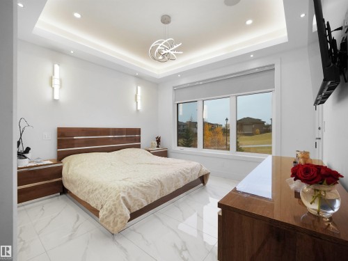 Tray ceiling with recessed lighting, integrated wall sconces, large windows, and a contemporary pendant light fixture - 4809 Woolsey Lane Nw, Edmonton, AB 