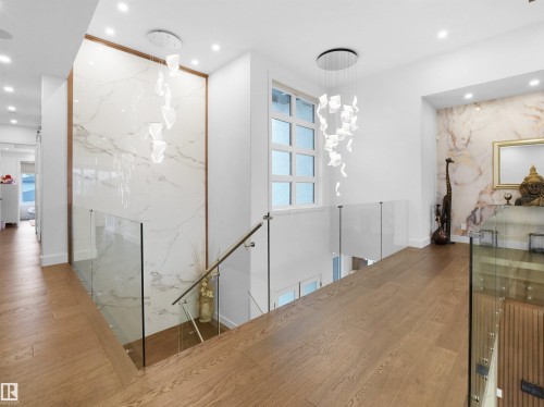 Hardwood flooring, glass railings, recessed lighting, decorative wall paneling, and a contemporary chandelier - 4809 Woolsey Lane Nw, Edmonton, AB 