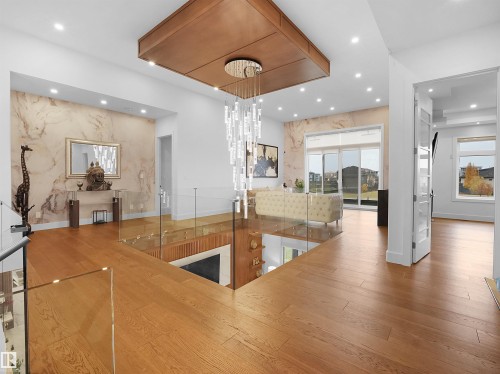 Hardwood flooring throughout, glass panel railing, recessed lighting, expansive sliding glass doors, and a decorative chandelier - 4809 Woolsey Lane Nw, Edmonton, AB 
