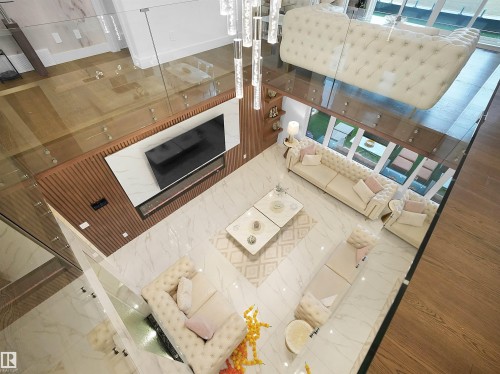 Open-concept living area with polished tile flooring and glass railings - 4809 Woolsey Lane Nw, Edmonton, AB 