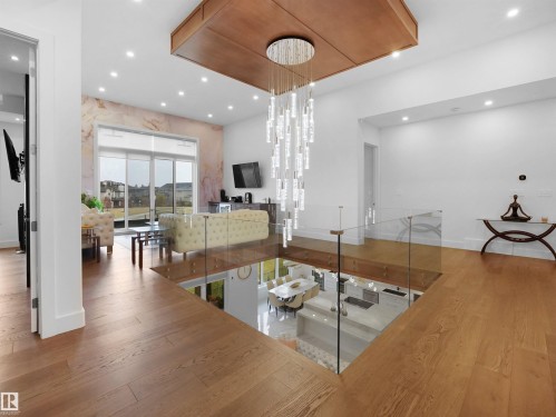 Wood-finish flooring, glass railing, recessed lighting, large glass slider, and a contemporary chandelier - 4809 Woolsey Lane Nw, Edmonton, AB 