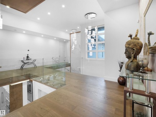 Hardwood flooring throughout, recessed lighting, glass railing, contemporary chandelier, and a large window - 4809 Woolsey Lane Nw, Edmonton, AB 