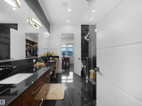Dual vanity with integrated sinks, dark wood-finish cabinetry, black marble-look countertops, and full-height mirrors - 4809 Woolsey Lane Nw, Edmonton, AB 