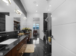 Dual vanity with integrated sinks, dark wood-finish cabinetry, black marble-look countertops, and full-height mirrors - 