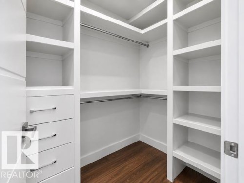 Walk-in closet with built-in shelving, integrated drawers with polished chrome hardware, and wood-finish flooring - 4809 Woolsey Lane Nw, Edmonton, AB 