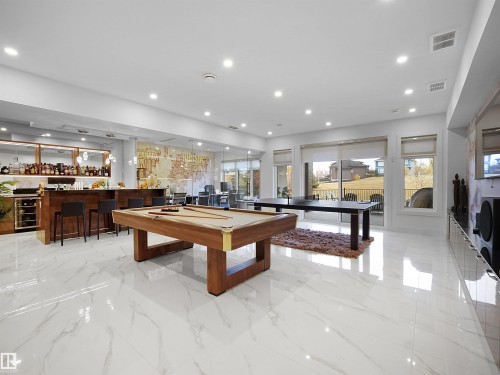 Spacious entertainment area featuring a built-in bar, pool table, and polished white tile flooring - 4809 Woolsey Lane Nw, Edmonton, AB 