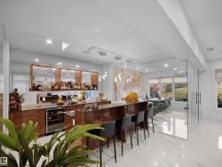 Integrated wet bar with beverage refrigerator, rich wood-finish cabinetry, and overhead storage - 