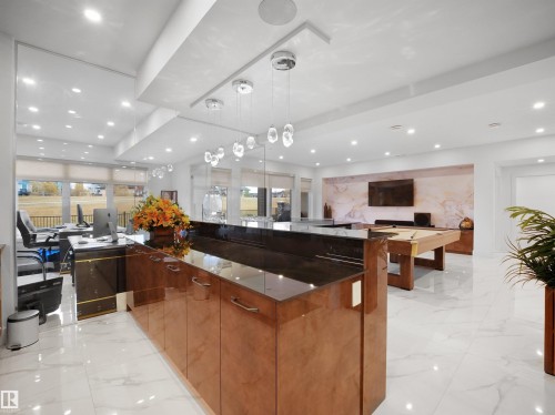 Expansive open-concept room featuring high-gloss cabinetry, large format tile flooring, a marble-effect accent wall, and recessed lighting - 4809 Woolsey Lane Nw, Edmonton, AB 