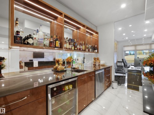 Built-in wet bar featuring a beverage refrigerator, integrated sink, dishwasher, and wood-finish cabinetry with accent lighting - 4809 Woolsey Lane Nw, Edmonton, AB 