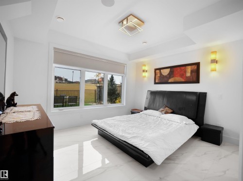 White marble-look flooring, large windows, recessed lighting, and wall sconces - 4809 Woolsey Lane Nw, Edmonton, AB 