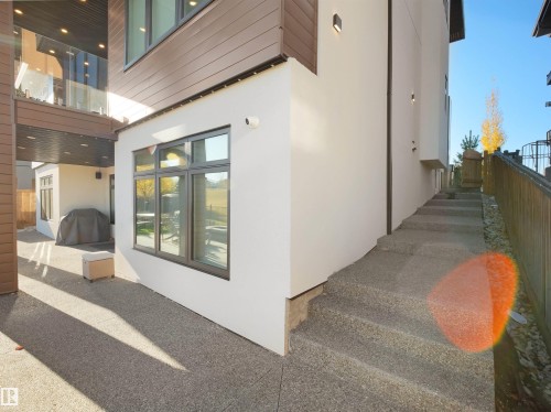 Exterior featuring stucco siding, wood-finish paneling, and multi-pane windows - 4809 Woolsey Lane Nw, Edmonton, AB 