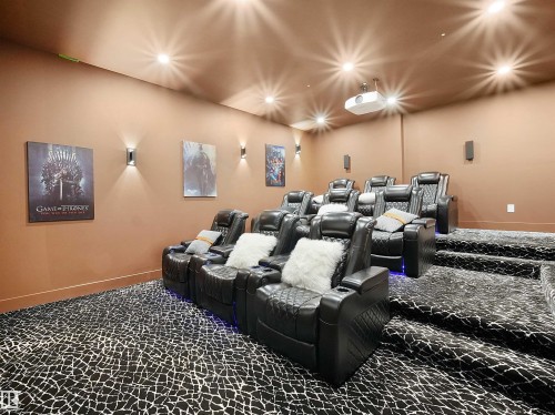Theater room featuring tiered seating, recessed ceiling lighting, a mounted projector, and wall-mounted sconces - 4809 Woolsey Lane Nw, Edmonton, AB 