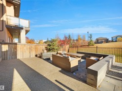 Expansive patio featuring a gravel-finish concrete surface and a paver stone seating area with built-in stone benches - 