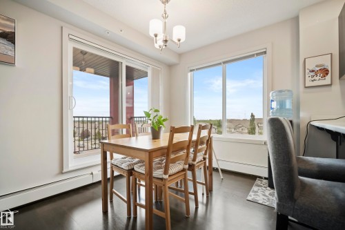 Dark wood-finish flooring, sliding glass door with balcony access, large window, and a ceiling-mounted light fixture - #419 5515 7 Av Sw, Edmonton, AB 