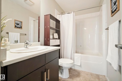 Bathroom featuring a white vanity countertop, undermount sink, dark wood-finish cabinetry, a built-in shower/tub combination, and tiled flooring - #419 5515 7 Av Sw, Edmonton, AB 